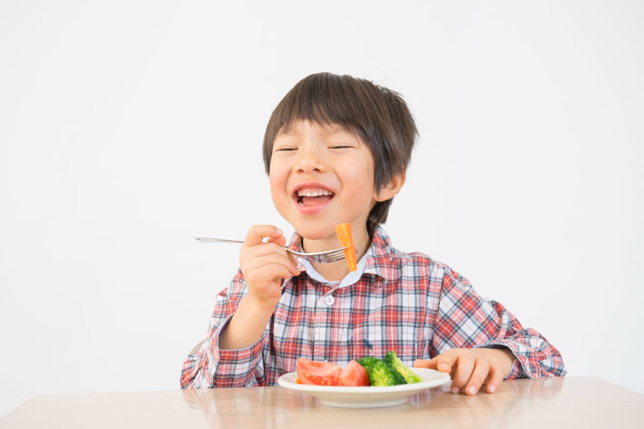 子どもが野菜を食べている画像