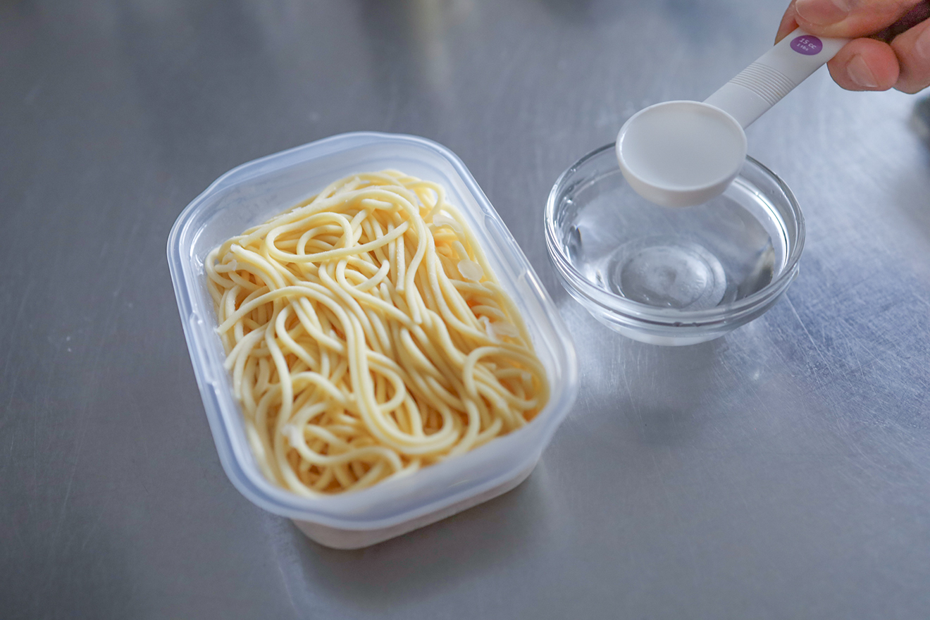 パスタに水をまわしかけている画像
