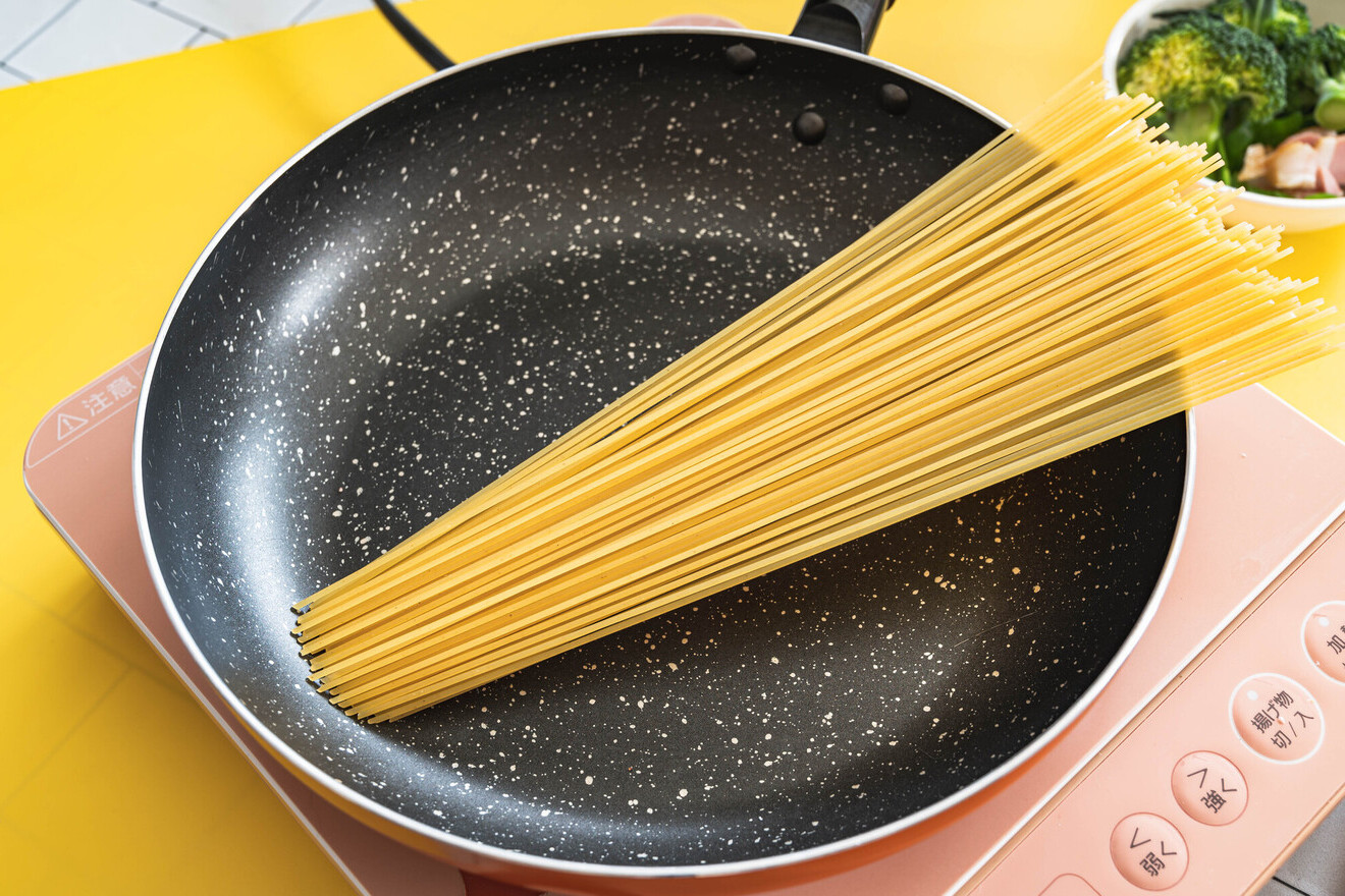 パスタをフライパンに入れている画像